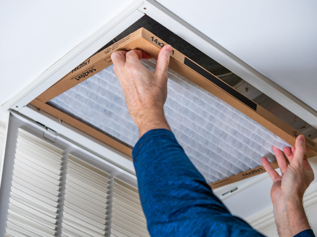 HVAC technician replacing a home air filter in San Mateo