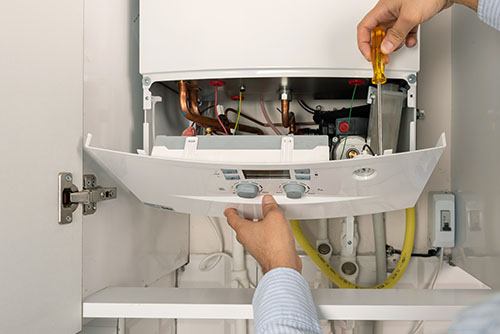 Heating technician repairing a residential boiler in San Mateo
