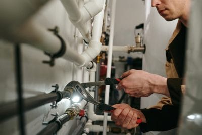 Technician inspecting commercial plumbing pipes in San Mateo