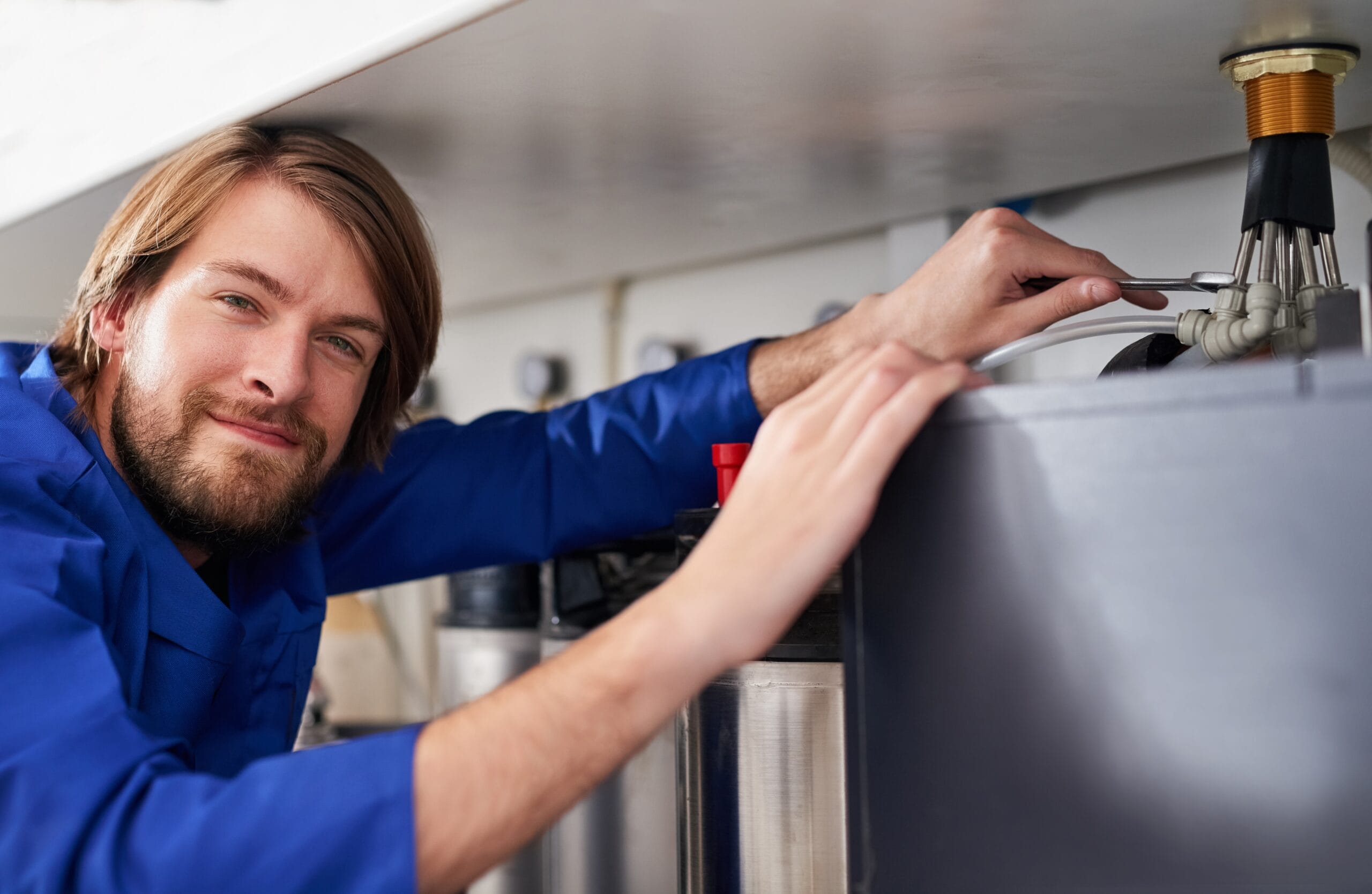 Technician servicing a residential water heater tank in San Mateo